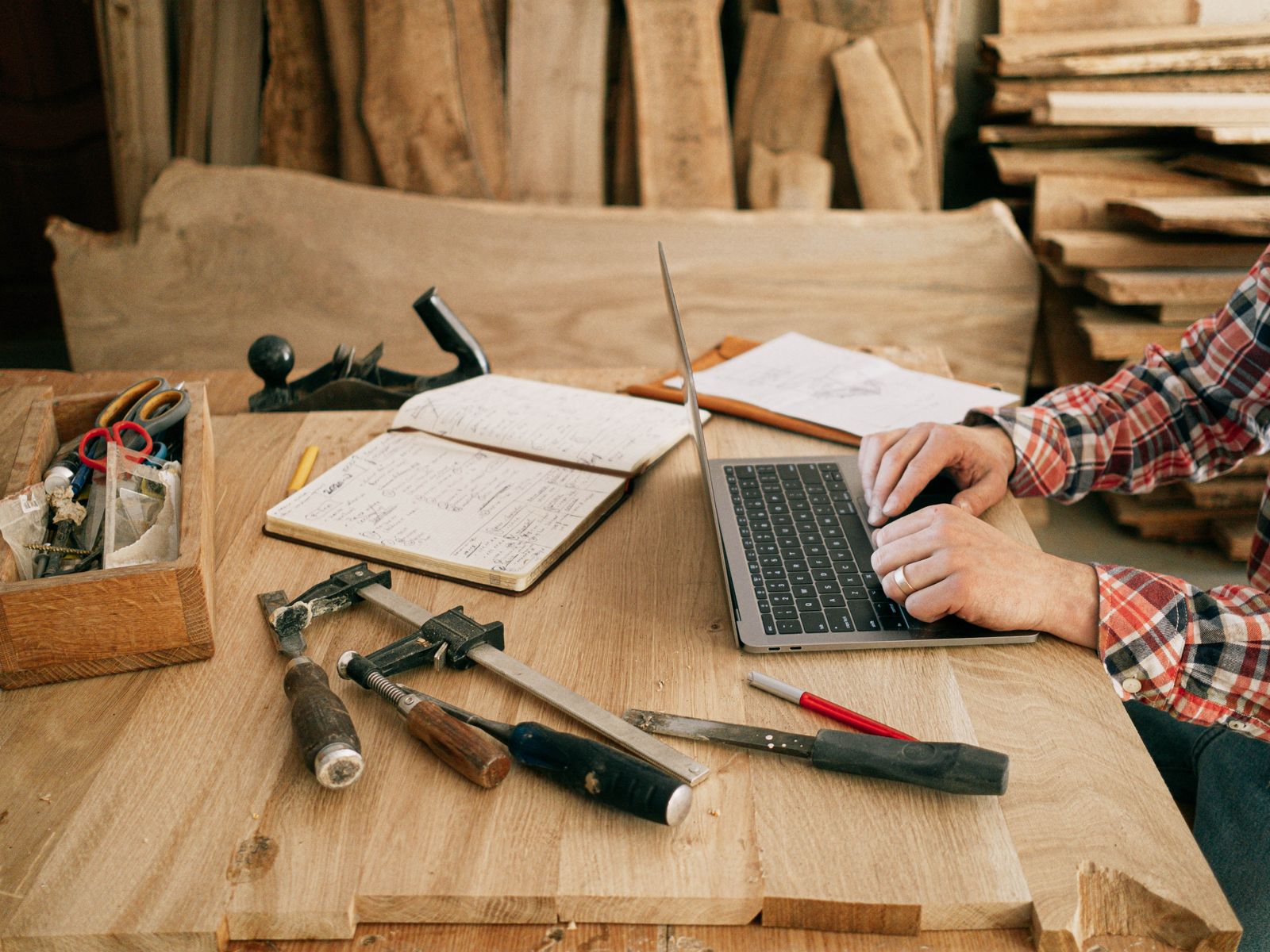 A carpenter checking a website on a laptop in their workshop