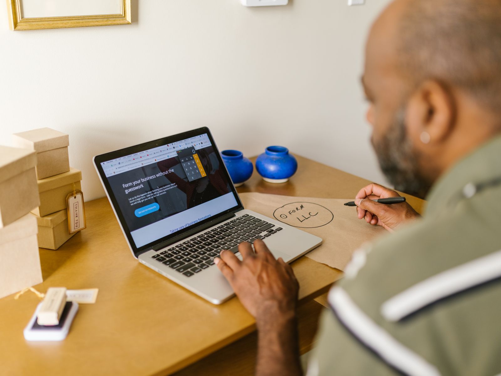 A small business owner planning at a laptop, shipping boxes nearby